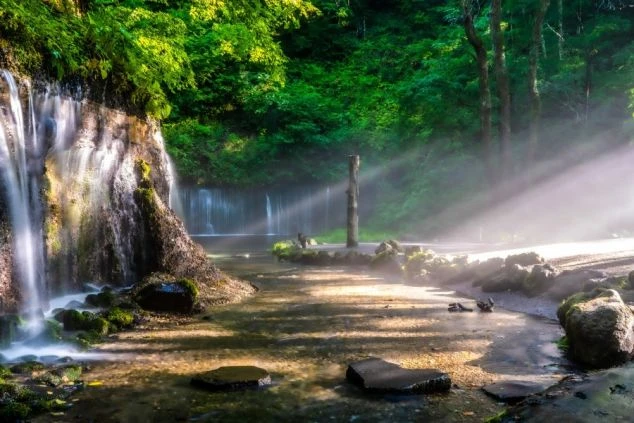 光芒が差し込む幻想的な滝の風景。リゾートバイトは、こんな自然の中で癒しを感じながら働けます。