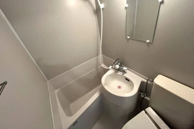 リゾートバイトの個室寮に備え付けのユニットバスの画像。浴槽、トイレ、洗面台が一体となった清潔な設備。