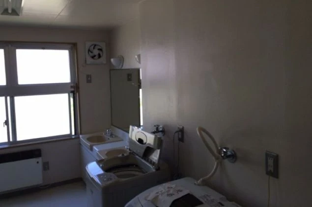 洗濯機と洗面台が設置された、清潔感のある共有スペース。生活に必要な設備が揃っており、快適に過ごせます。