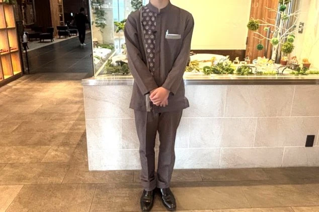濃い茶色のアジアンテイストな制服を着用した男性スタッフの画像。制服の胸元には柄が入ったデザインレストランサービススタッフの制服の画像。