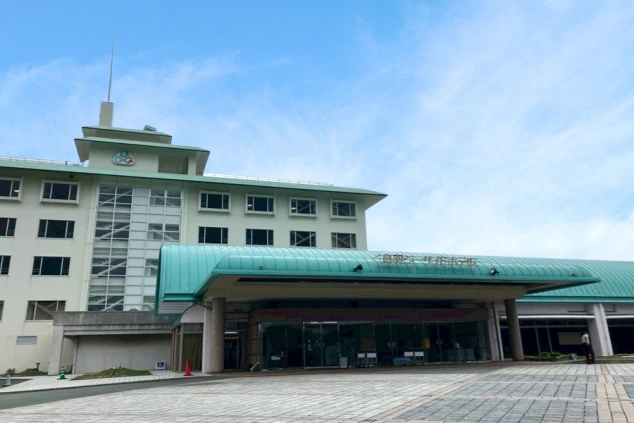 薄緑色の屋根と白い外壁が特徴的な、広々としたエントランスと建物外観