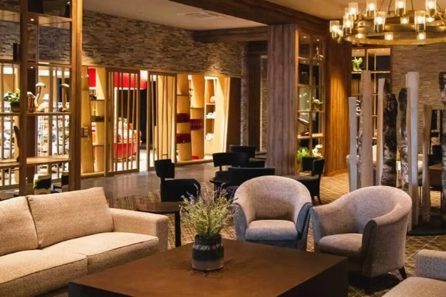 石壁と木材を基調とした、モダンで落ち着いた雰囲気のホテルのラウンジの画像。ソファや椅子が配置され、間接照明が灯っている。リゾートバイトの仕事場となるホテルの共有スペースの画像。