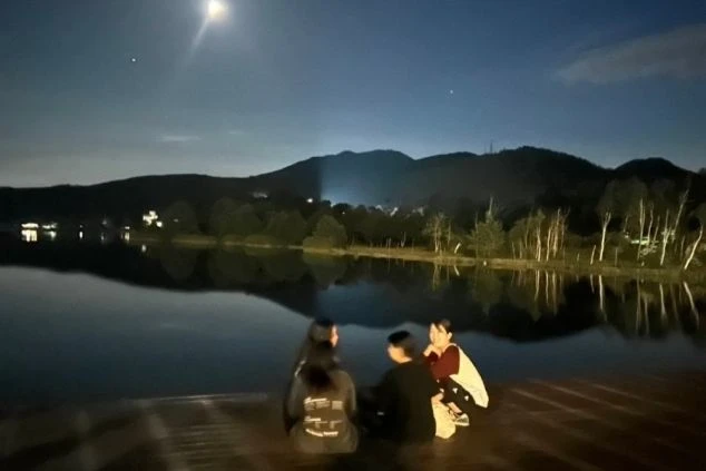 夜の湖畔のデッキに座って、夜景を眺めている若い男女のシルエット画像。リゾートバイトの休日の過ごし方やリゾート地の風景を表すワクトリスタッフが撮影したオリジナル画像。