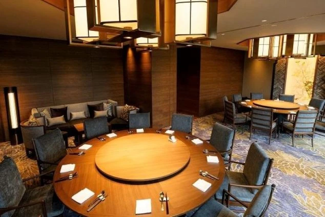  リゾートホテルの高級レストランのダイニングスペース。落ち着いた照明と円卓が特徴的な空間。ホールスタッフや宴会サービスの仕事場。