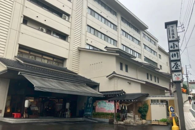 小川屋の建物正面と、道路脇に立つ「下呂温泉 小川屋 入口」の縦長看板。和風の庇と洋風の建物が組み合わさった外観。