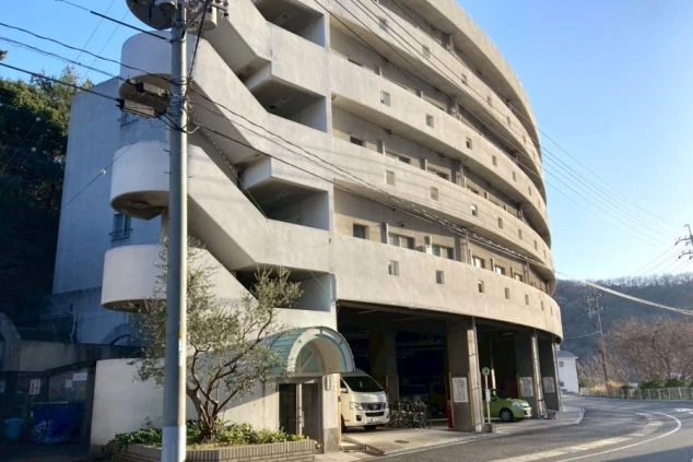 リゾートバイトの寮の外観。海辺の温泉地に建つ円形の建物で、エレベーターや非常階段が完備された集合住宅。