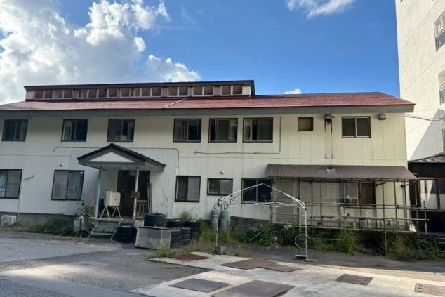 寮の外観。山間に建つ集合タイプの建物で、住み込みで働くための寮。