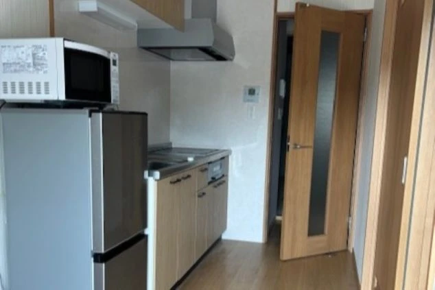 リゾートバイトの寮の個室にある、モダンなキッチン。IHコンロや電子レンジ、冷蔵庫が完備されており、自炊に便利です。