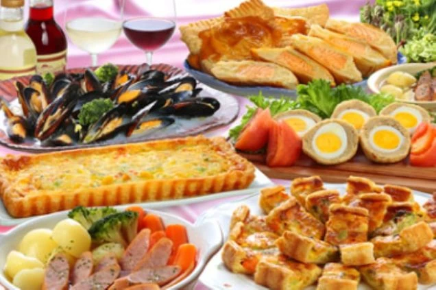 キッシュ、ミートパイ、ムール貝など、豪華な西洋料理の数々がテーブルに並べられた画像。手前にはワインボトルとグラスも写っている。ホテルレストランで提供される料理を表す画像。