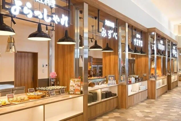 木目調の内装とネオンサインが特徴的なフードコートのようなレストランの画像。ビュッフェカウンターが並び、おしゃれな雰囲気を醸し出している。リゾートバイトの仕事内容を表す、ホテルのダイニングの画像。