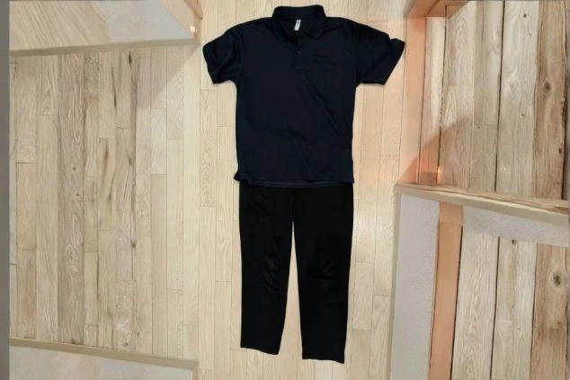 裏方スタッフの制服画像。動きやすいネイビーのポロシャツと黒のスラックスのセット。