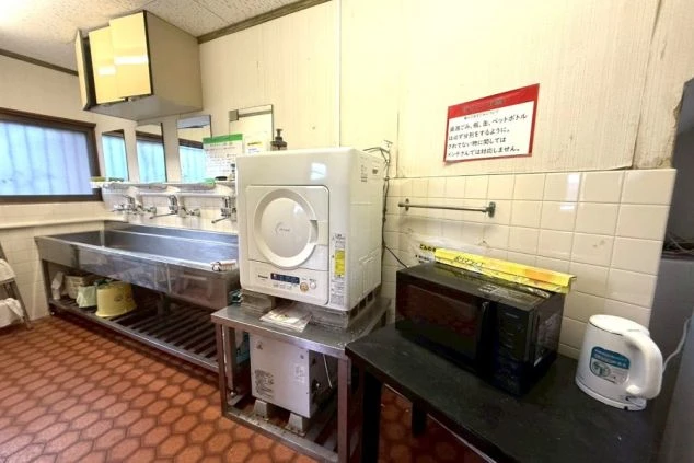リゾートバイト寮の共用設備。電子レンジや電気ポット、乾燥機などが設置されており、生活に必要な家電が充実。