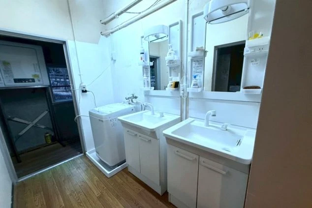 リゾートバイト寮の清潔な洗面所。使いやすい独立洗面台と洗濯機を完備しており、身支度もスムーズに行える設備。