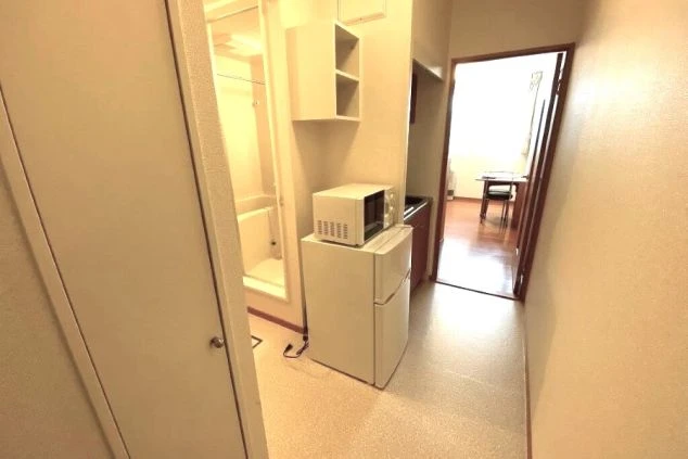 リゾートバイトの寮の玄関・キッチンエリア。冷蔵庫や電子レンジがあり、コンパクトながらも生活しやすい造りになっています。