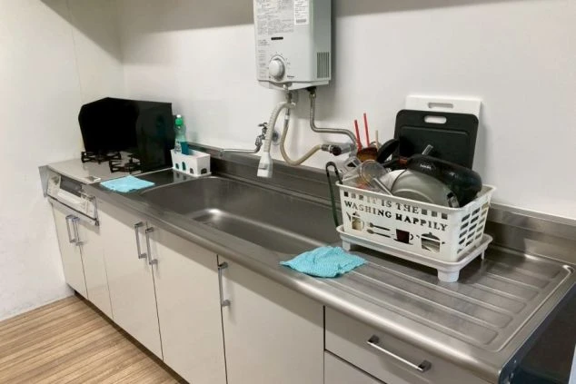 ワクトリの社員が出張で撮影した、リゾートバイトの寮のキッチンの画像。シンクの右側には洗った皿や調理器具、左側にはコンロが見える。