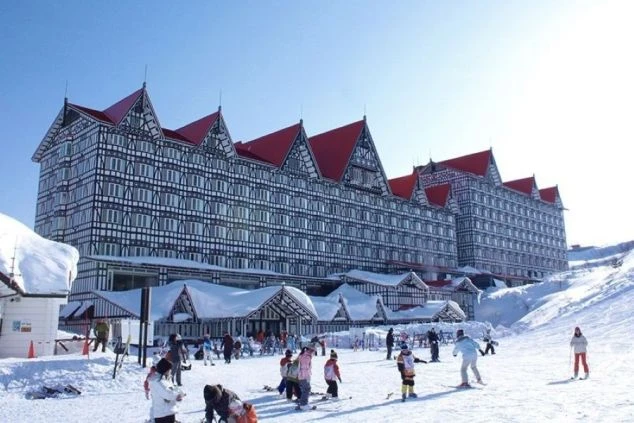 スキー場ホテルの外観。雪に覆われたゲレンデと洋風の建物。冬のリゾートバイトの仕事場のイメージ。