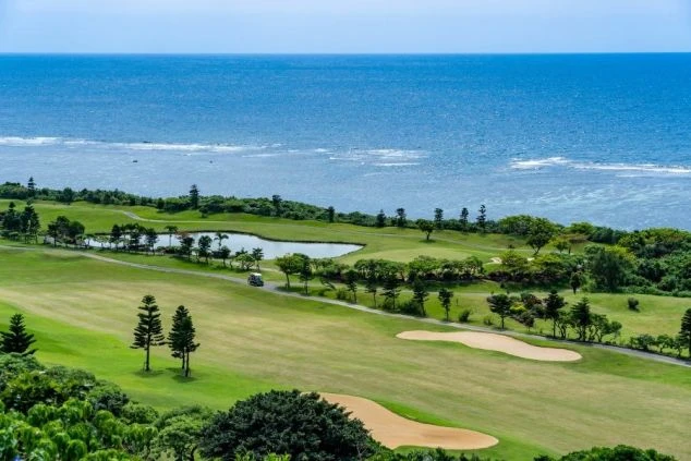 青い海が隣接する絶景ゴルフ場の写真。ゴルフ場でのリゾートバイトでは、南国の非日常的なリゾート環境で働ける魅力を伝えます。