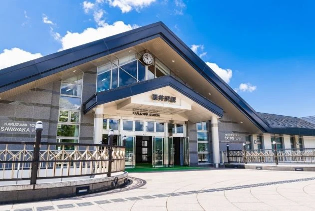 夏の青空の下にある軽井沢駅の駅舎の画像。長野県軽井沢エリアのリゾートバイト探しをイメージ。
