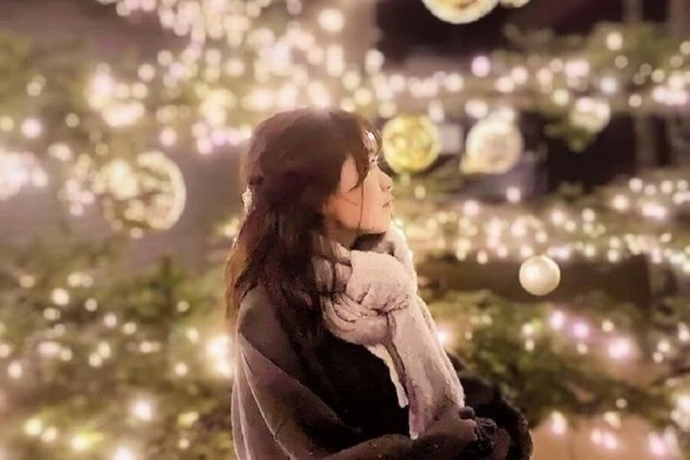 冬のイルミネーションを背景にマフラーを巻いた女性の画像。リゾートバイトの休日に観光を楽しむイメージ。