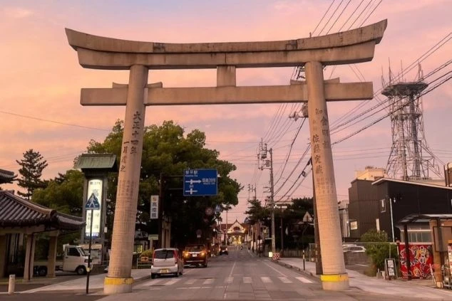 夕焼けに染まる空の下、大きな鳥居が立つ街並み。リゾートバイトの休日には、観光名所を巡って最高の思い出を作れます。