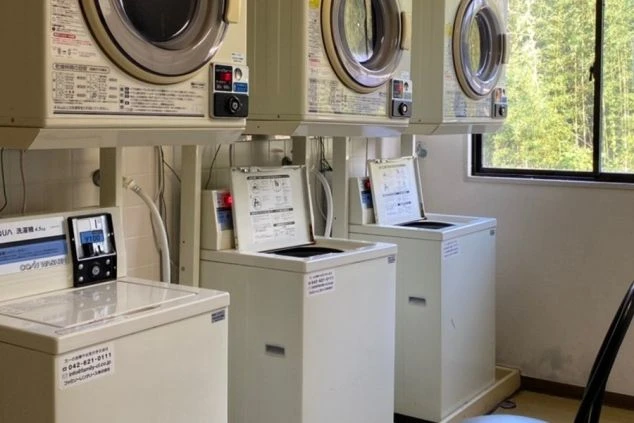 リゾートバイトの寮の共用ランドリー。コイン式の洗濯機と乾燥機が複数台設置されており、いつでも洗濯が可能です。