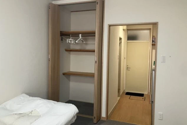 スタッフ寮にある、広々としたクローゼット収納の画像。ハンガーラックと上部の棚が完備されている。