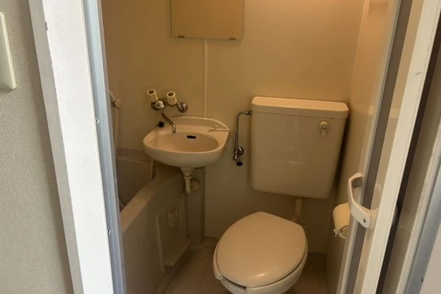 浴槽とトイレ、洗面台が一体となった寮のユニットバスの画像。