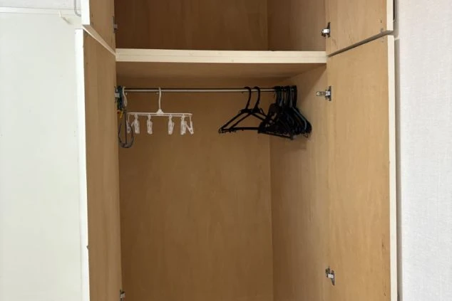 ハンガーとクリップハンガーが入った寮のクローゼットの画像。