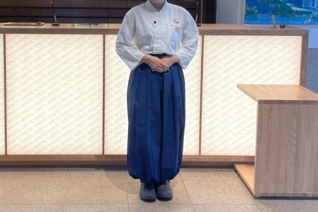 女性の制服。清潔感のある白い上着に紺色のゆったりとしたズボン。