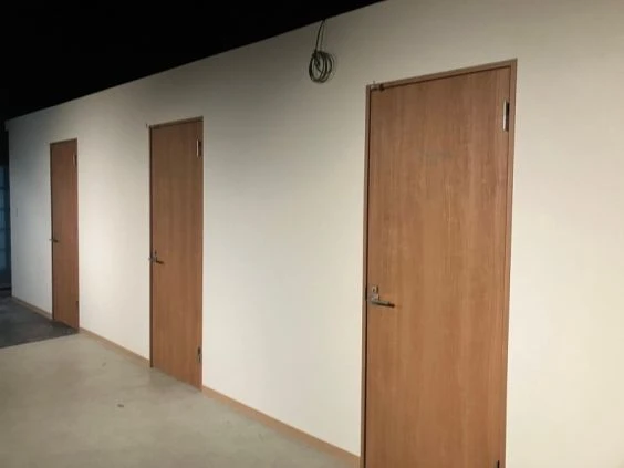 寮の共用廊下。木目調の扉が複数並び、各部屋へ続く様子が映る。