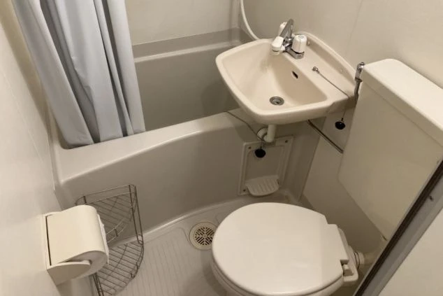寮のユニットバス。浴槽、洗面台、トイレがコンパクトに一体化した、一般的なデザインの浴室。