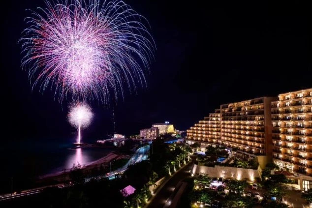 ホテルから望む夜景と、海辺で打ち上がる鮮やかな花火。