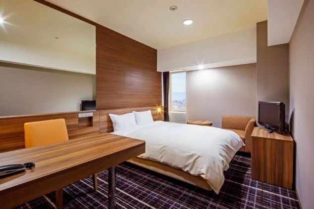 寮の部屋の画像。和室で畳が敷かれ、布団、座卓、テレビが置かれている。