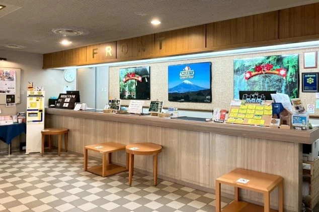 木目調の長いフロントカウンターがあるホテルのロビー。壁には富士山や景勝地の写真が飾られている。