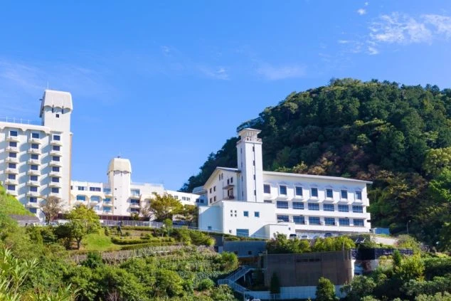 緑豊かな丘の上に建つ、白を基調としたモダンな雰囲気のホテル外観。