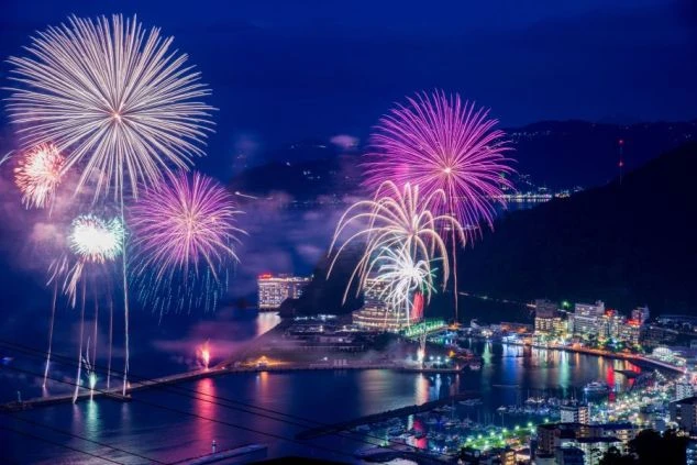 煌めく夜景を背景に、色とりどりの花火が打ち上がる熱海海上花火大会。