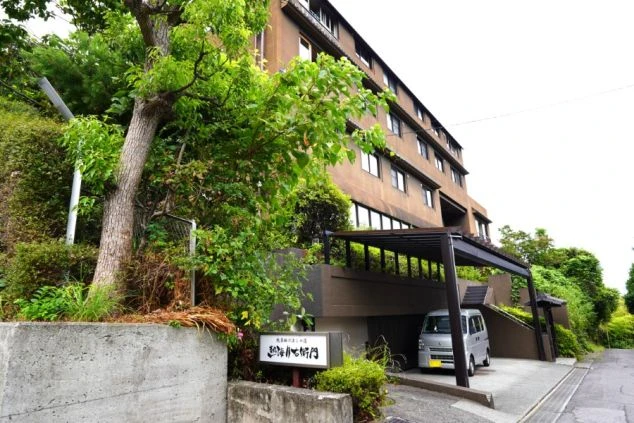 リゾートバイトの勤務先の外観を表現するイメージ画像。豊かな緑に囲まれた高台に立つ落ち着いた茶色の建物
