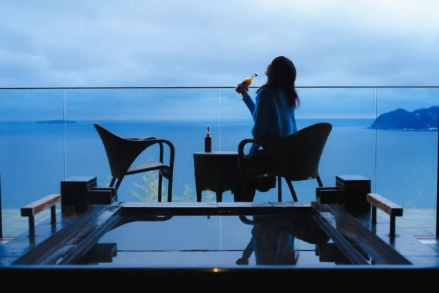 海を眺めてドリンクを飲む女性。リゾートバイトの休日の過ごし方。