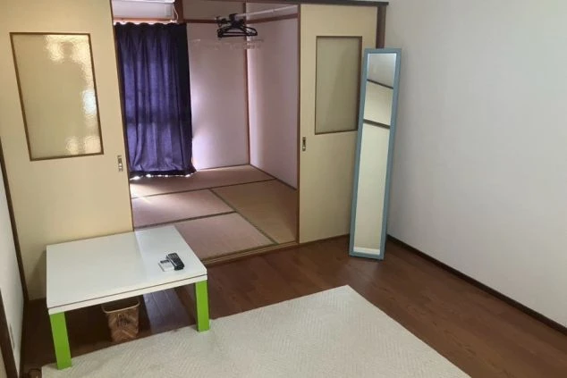 リゾートバイトの寮の間取り。洋室と和室が繋がった広々とした部屋。姿見とテーブルが置かれた、家具家電付きの寮。