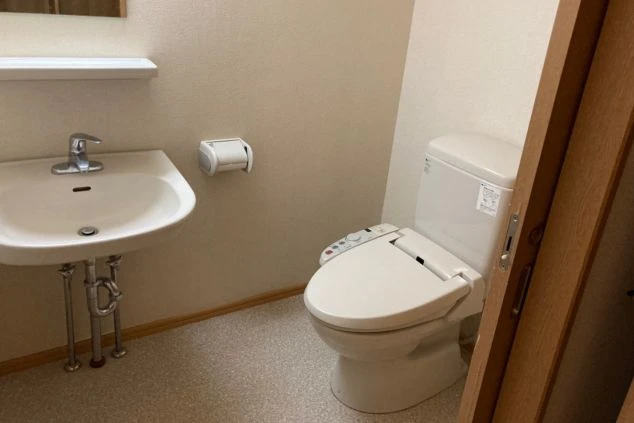 リゾートバイトの寮のトイレの画像。ウォシュレット付きの便座と、洗面台がまとまって配置されている。リゾートバイトの寮のトイレの画像。