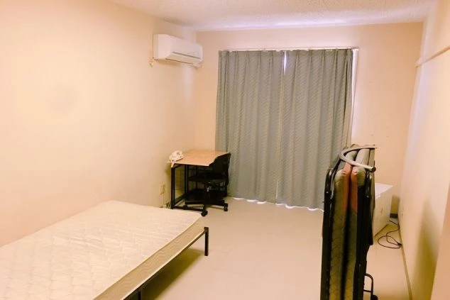 沖縄でリゾートバイトをするスタッフが住む寮の画像。寝具や青いカーテンがある。