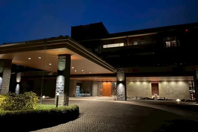 木々の緑に囲まれた、モダンな和風建築のホテル外観。