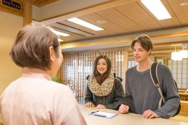 リゾートバイトのフロント業務。外国人観光客を笑顔で接客。語学力（英語など）を活かして国際交流ができる仕事のイメージ画像。