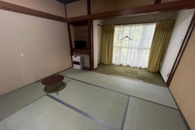 リゾートバイト女性寮の広々とした個室(洋室)の画像。カーペット敷きで収納棚や大きな窓があり、開放的な空間。