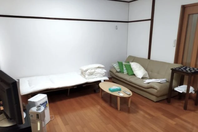 リゾートバイトの寮の室内写真。ソファとベッド、テレビ、テーブルが整ったきれいな個室で、ゆったりとくつろげます。