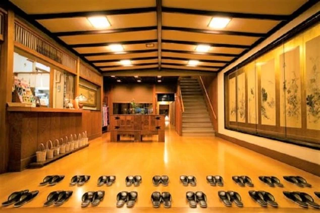 和風旅館の広々とした玄関（ロビー）。下駄が整然と並び、帳場、階段、金屏風がありリゾートバイトの勤務先の雰囲気を示す写真。
