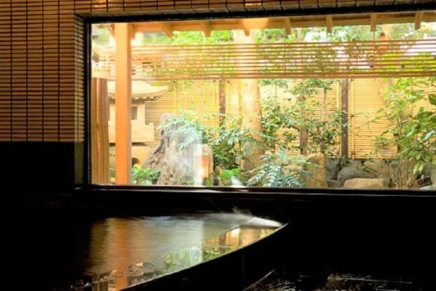 窓の外に日本庭園が広がる旅館の内湯（温泉）。湯気が立ち上る浴槽があり、リゾートバイトのスタッフ特典などで利用できる温泉のイメージ。