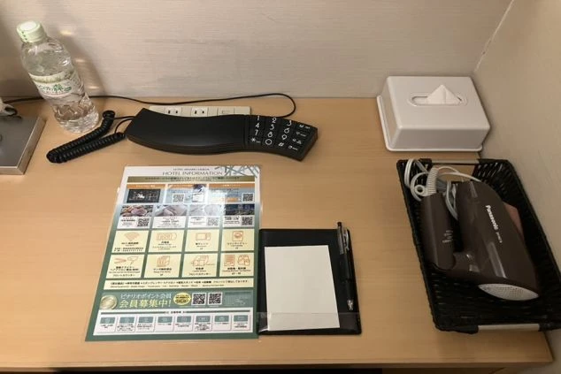 リゾートバイトの寮(客室タイプ)のデスク周り。電話、ドライヤー、ティッシュ、メモ帳などが用意されており、ホテルの客室のように快適です。