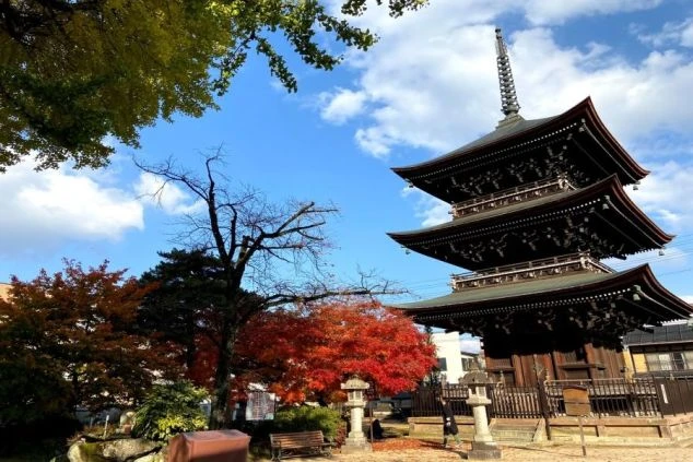 岐阜県飛騨高山にある「飛騨国分寺」の三重塔と、赤く色づいた紅葉の画像。リゾートバイトのオフシーズンや休日に日本の歴史や四季折々の美しい景色を楽しむ。