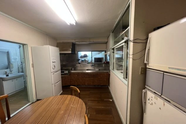 リゾートバイト寮の共用キッチンの画像。冷蔵庫やダイニングテーブル、調理スペースのある共用部画像。